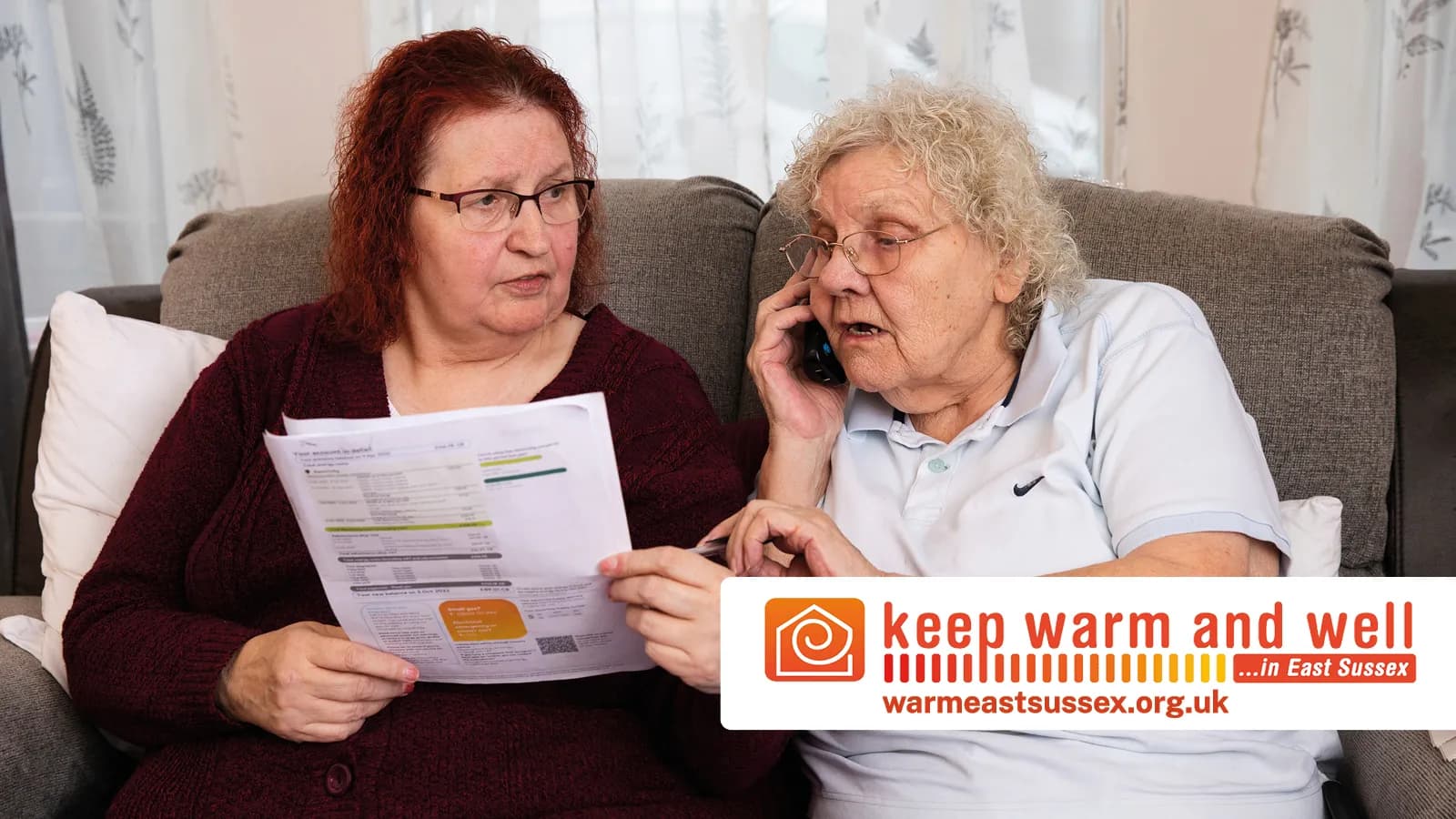 Two women, one reading a document and the other talking on a phone, appear concerned while sitting on a couch.